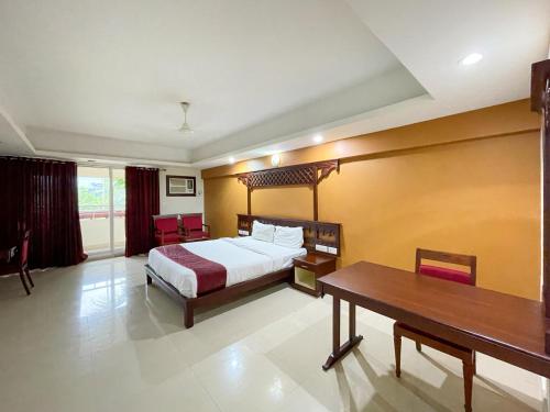 a bedroom with a bed and a desk and a table at Haveli Backwater Resort in Alleppey