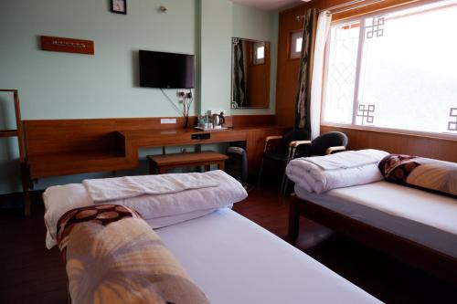 a hotel room with two beds and a desk at Hotel Mon Paradise in Tawang