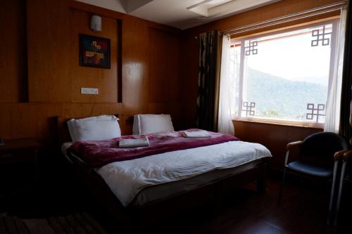 a bedroom with a large bed with a window at Hotel Mon Paradise in Tawang