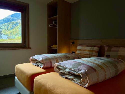 1 Schlafzimmer mit 2 Betten mit Kissen und einem Fenster in der Unterkunft Chalet Girasole in Livigno
