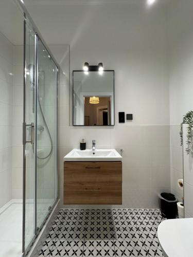 a bathroom with a sink and a shower with a mirror at Kamienica Ogrodowa Rooms in Sopot