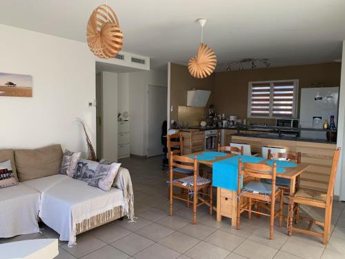 un salon avec un canapé et une table et une cuisine dans l'établissement Maison 6 pers, climatisée, quartier calme, proche Dune du Pyla et pistes cyclables, ménage inclus - FR-1-319-426, à Parentis-en-Born