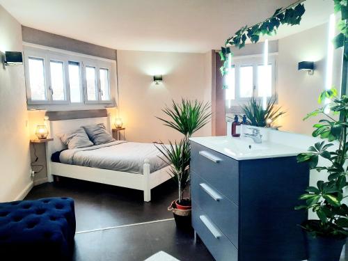 a bedroom with a bed and a sink and plants at L'Élégant in Douvaine