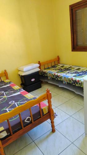 dwa łóżka w pokoju z żółtymi ścianami w obiekcie Casa de praia para família - 3 quartos - acomoda até 10 pessoas w mieście Tramandaí