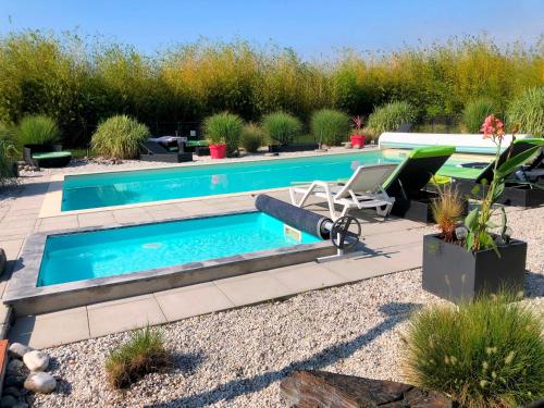 una piscina en un patio con 2 sillas y una mesa en Gîte en Lot-et-Garonne avec piscine et jardin de 6000m2, en Bourran