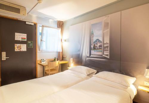 1 dormitorio con 2 camas, mesa y ventana en B&B HOTEL Limoges 2, en Limoges