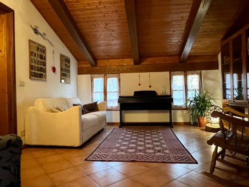a living room with a couch and a piano at Appartamento immerso nella natura, silenzio e riservatezza a 550 m di quota in Langhirano