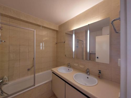 a bathroom with two sinks and a tub and a mirror at Studio Zeedijk Koksijde in Koksijde