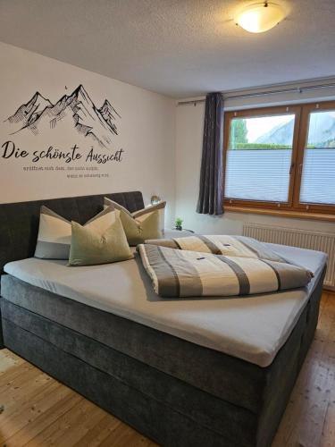 1 cama grande en un dormitorio con un cartel en la pared en Ferienwohnung Sturm Pitztal, en Enzenstall