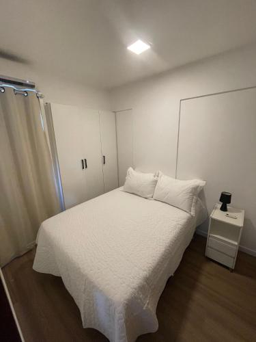 Loft Residencial GreenPark by Staya في برازيليا: غرفة نوم مع سرير مع ملاءات بيضاء وخزانة
