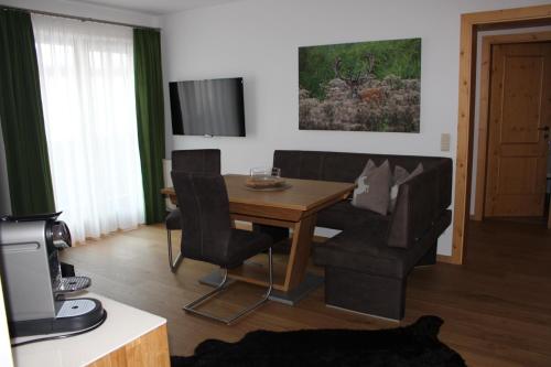 Apartments Embach في امباخ: غرفة معيشة مع طاولة وكراسي وتلفزيون