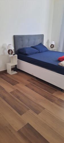 a bedroom with a bed with blue sheets and wood floors at CASA DUPLEX EM PENEDO 4 SUÍTES,FINS DE SEMANA e FERIADOS in Itatiaia