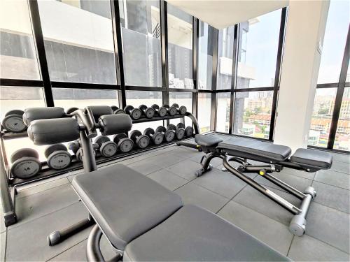 a gym with a bench and weights in a room with windows at Modern Elegance Suite, 5 to 6 pax at Urban Suites Georgetown by SuperStay in Jelutong