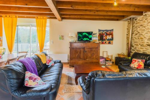 a living room with two leather couches and a television at Gite de charme, idéal pour 4 in Saint-Jory-de-Chaleix