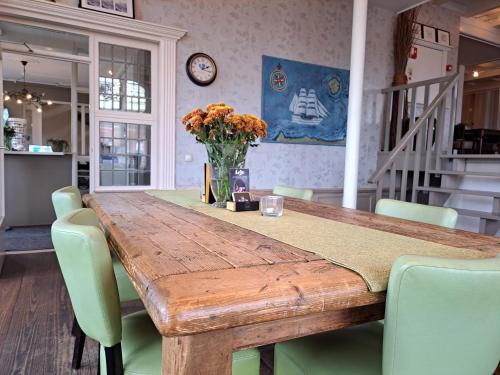 a wooden table with chairs and a vase of flowers at Hotel Restaurant Boven Groningen in Delfzijl