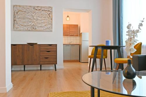 a living room with a table and a kitchen at Gemütliches Stadtapartment im Zentrum von Ried im Innkreis in Ried im Innkreis