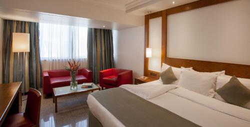 a hotel room with a bed and a red chair at Eko Hotel Gardens in Lagos
