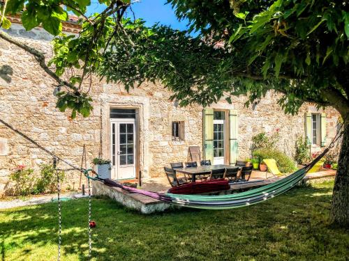 una hamaca en el patio de una casa de piedra en Gîte en Lot-et-Garonne avec piscine et jardin de 6000m2, en Bourran