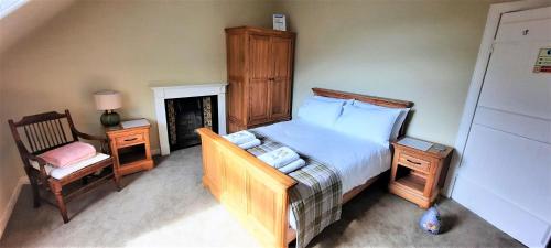 a bedroom with a bed and a chair and a fireplace at Glenterry Farmhouse in Kirkcudbright