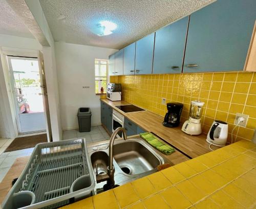 a kitchen with a sink and yellow tiles on the wall at South Finger Villa in Jolly Harbour