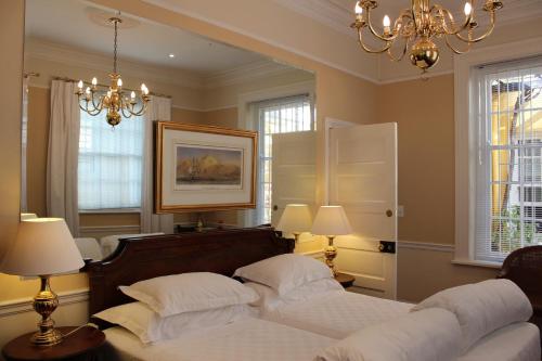 1 dormitorio con 2 camas, 2 lámparas y una lámpara de araña en Tintagel Guesthouse, en Ciudad del Cabo