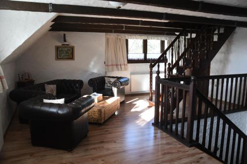 a living room with black leather furniture and a staircase at Sári Udvar in Dunakiliti