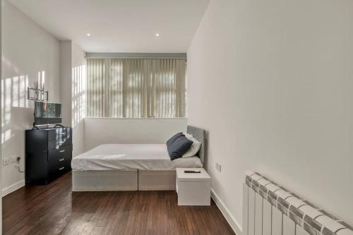 a white bedroom with a bed and a window at Chic 1 Bedroom Apartment in London