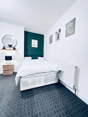 a bedroom with a white bed and a green wall at Vinery Green Long Stay Offers in Knowsthorpe