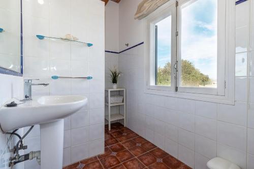 baño blanco con lavabo y ventana en Villa La Palmera By homevillas360, en Pollensa