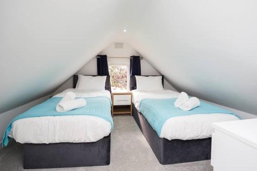 a attic bedroom with two beds and a window at The White Cottage at Gildridge + Private Hot Tub+EV in Chiddingly