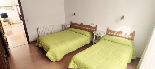 two beds in a room with green sheets at Casa Carmen in Faraján