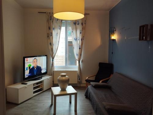 uma sala de estar com um sofá e uma televisão em Le Grèbe em Le Tréport
