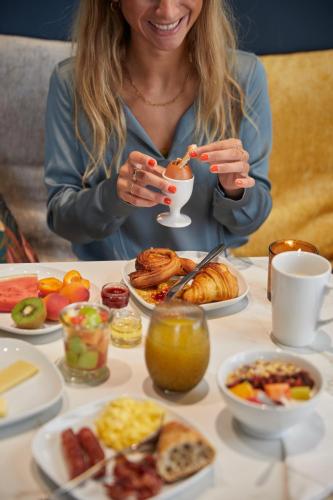 a woman sitting at a table with plates of food at Best Western Hotel du Pont Wilson in Lyon