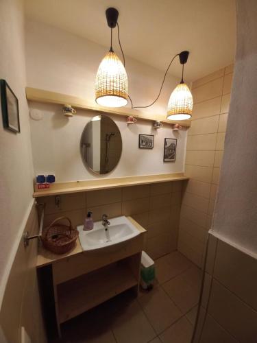 La salle de bains est pourvue d'un lavabo, de deux lumières et d'un miroir. dans l'établissement Casa Edelweiss - Gyopár - Flore de colt, à Rimetea