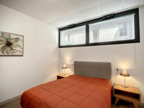 - une chambre avec un lit rouge et deux fenêtres dans l'établissement Appartement F3 Climatisé PMR à 50m des Thermes avec Terrasse et Parking, Animaux Acceptés - FR-1-451-170, à Lamalou-les-Bains