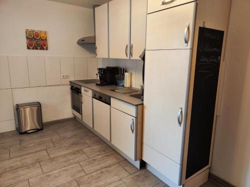 Una cocina con gabinetes blancos y un refrigerador. en Wohlfühloase Mönchengladbach 1, en Mönchengladbach