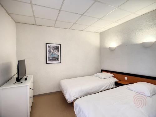 une chambre d'hôtel avec deux lits et une télévision dans l'établissement Séjour Idéal à Lamalou: Studio 28 m², Balcon, Proche Thermes, Animaux Acceptés, Wifi Inclus - FR-1-451-182, à Lamalou-les-Bains