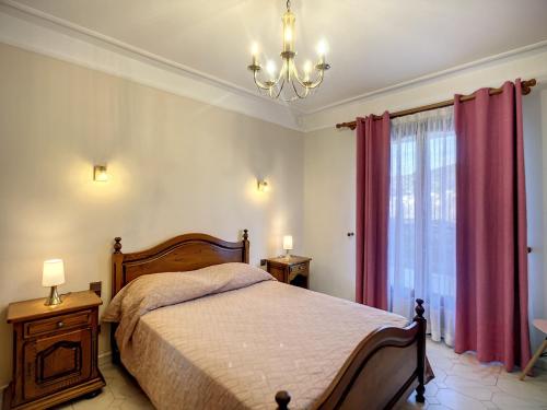 a bedroom with a bed with red curtains and a chandelier at Maison Lamalou-les-Bains, 5 pièces, 6 personnes - FR-1-451-185 in Lamalou-les-Bains