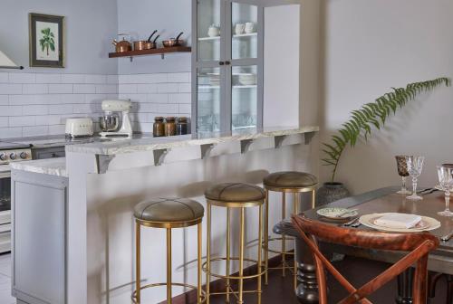 a kitchen with a bar with stools and a table at One&Only Gorilla's Nest in Kinigi