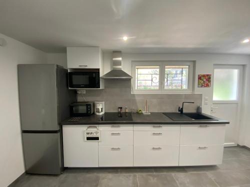  La cuisine est équipée de placards blancs et d'un réfrigérateur. dans l'établissement Rez-de-chaussée rénové avec jardin clos, à 1,6 km de la plage, idéal pour 2 adultes et 2 enfants - FR-1-364-142, à Saint-Brévin-les-Pins