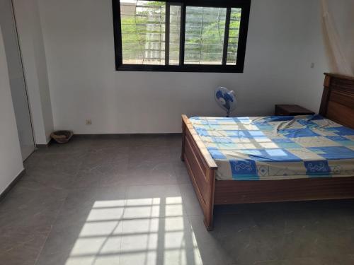 een slaapkamer met een bed in een kamer met een raam bij Villa Sylla fall in Toubab Dialaw