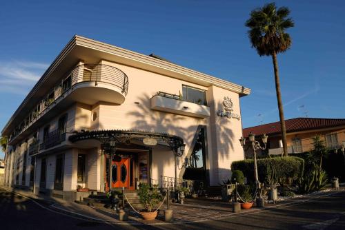 a white building with a palm tree in front of it at Hotel Bellavista in Marina di Varcaturo