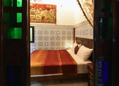a small bedroom with a bed and a painting on the wall at Dar Aya Fes in Fès