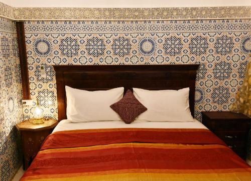 a bedroom with a bed with a patterned wall at Dar Aya Fes in Fès
