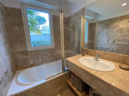 La salle de bains est pourvue d'un lavabo, d'une baignoire et d'une fenêtre. dans l'établissement Appartement T2 en Front de Mer à Arcachon, Accès Direct Plage, Parking, Animaux Admis - FR-1-374-201, à Arcachon