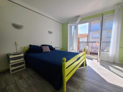 een slaapkamer met een blauw bed en een balkon bij Appartement Argelès-sur-Mer, 2 pièces, 4 personnes - FR-1-309-371 in Argelès-sur-Mer