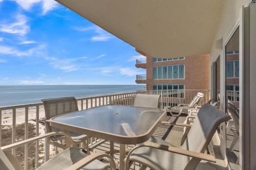 a balcony with a table and chairs and the ocean at Three-Bedroom Apartment in Orange Beach