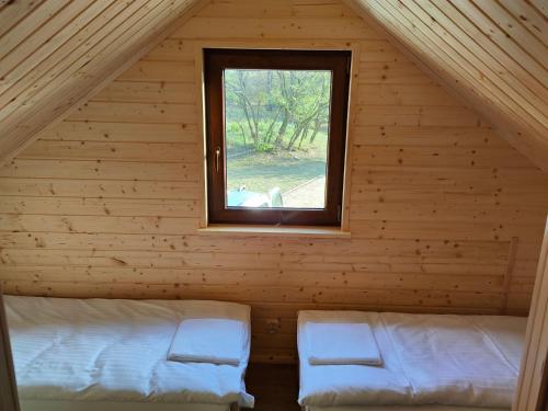 a room with two beds in a log cabin with a window at Domki Dygudaj 