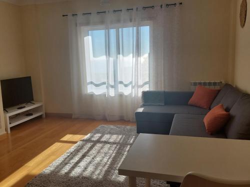 a living room with a blue couch and a window at Sesimbra TOP in Sesimbra