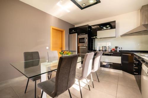 a kitchen with a glass dining table and chairs at Casa Mia, a Dream Spot With Heated Pool in Arco da Calheta